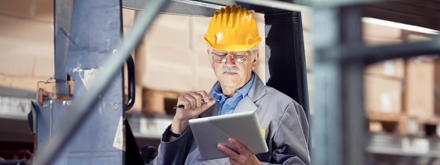 man with hardhat looking at tablet, sitting on cart