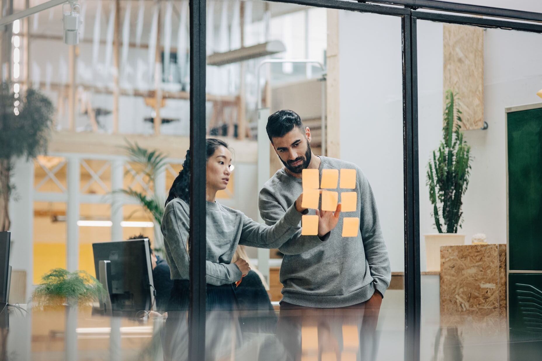 Woman and man pointing at stickies on a glass wall