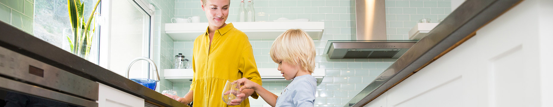 mother handing glass to child in kitchen