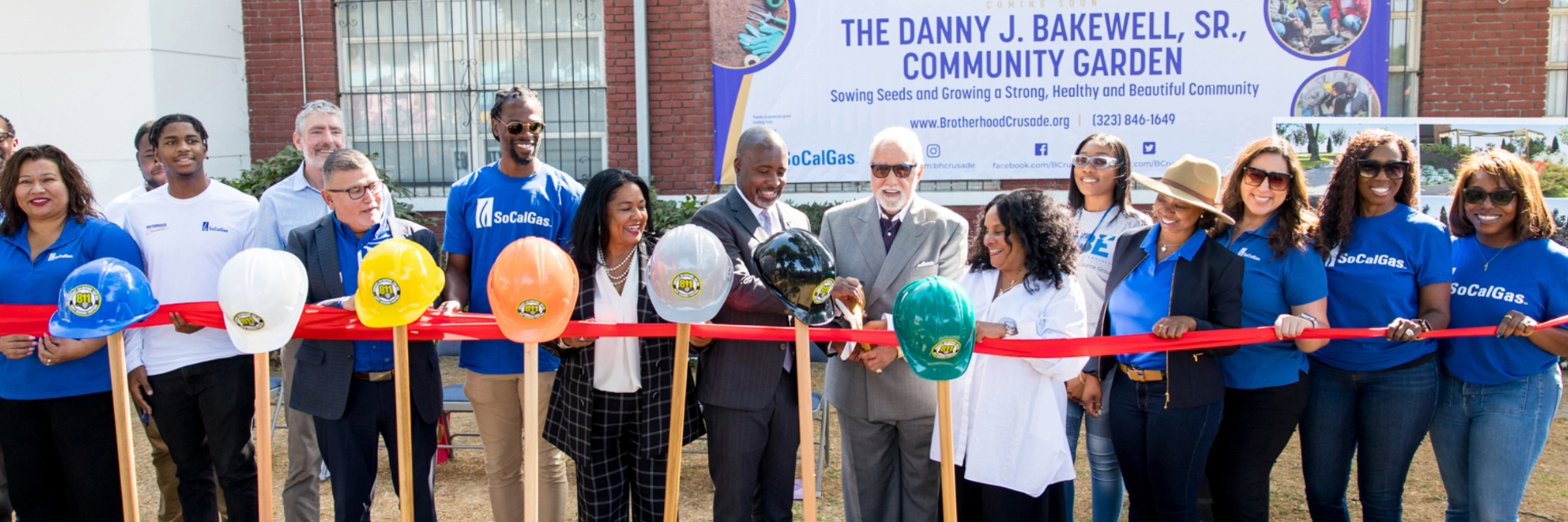 People holding hats and shovels at ribbon cutting ceremony.