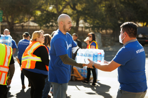 SoCalGas employee volunteering with two employees in the foreground exchanging a case of water