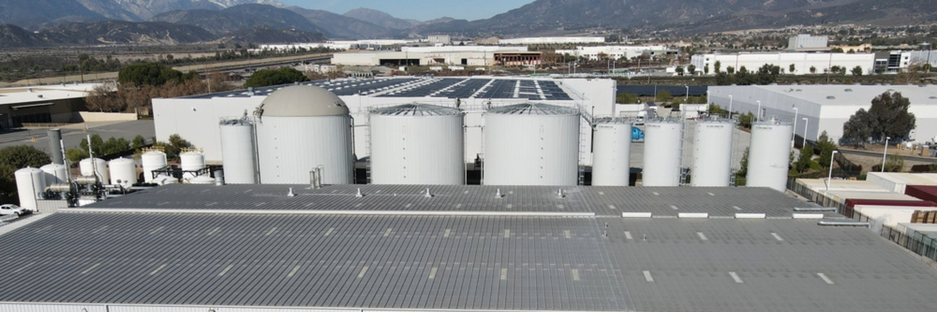 Image of a building with silos behind it and mountains in the background