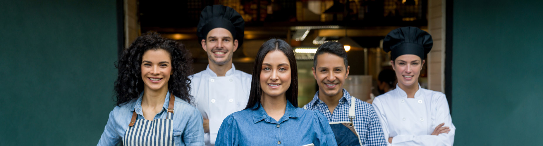 kitchen staff in front of building smiling