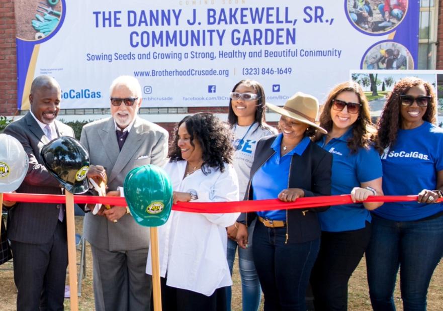 People holding hats and shovels at ribbon cutting ceremony.