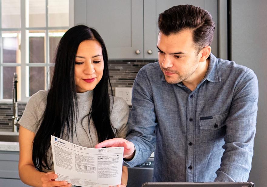 A couple looking at their utility bill in their kitchen