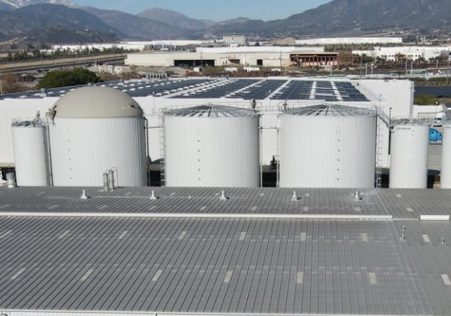 Image of a building with silos behind it and mountains in the background